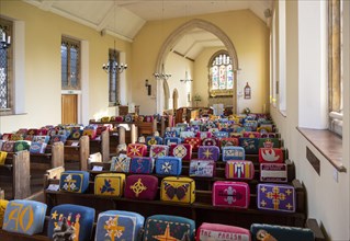 Village parish church Chelmonidiston, Suffolk, England, UK bright knitted woollen kneelers on pews