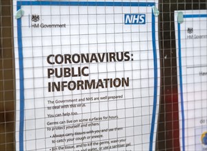 National Health Service NHS government information Coronavirus notice glass door entrance to GP