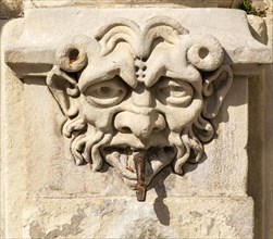 Carved stone face on old fountain in Cuenca, Castille La Mancha, Spain snake spout emerging from