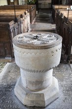 Simply decorated stone 12th century baptismal font inside church at Stanton St Bernard, Wiltshire,