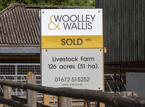 Estate agent Woolley and Wallis property sold sign at livestock farm near Potterne, Wiltshire,