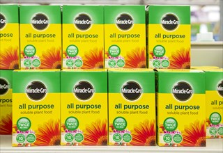 Cardboard boxes of Miracle-Grow all purpose soluble plant food on shelf display in garden centre,