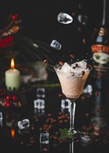 An atmospheric picture with a drink, Baileys in a glass, ice cube cubes and coffee beans