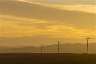 Evening light over fields near Krebs in the Osterzgebirge, electricity pylons can be seen