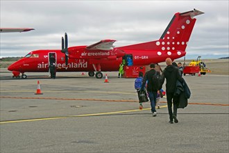 Passengers walk to a propeller plane across a tarmac, Air Greenland, Ilulissat, Greenland, Denmark,