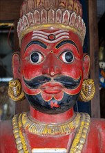 A close-up of a traditional red-faced statue of a man with a mustache, Matancherry, Jew Town,