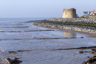 Martello Tower Y low tide protected by rock armour coastal defences, Bawdsey, Suffolk, England, UK,