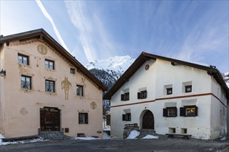 Historic houses, sgraffito, facade decorations, window shutters, mountain peaks with snow, winter,