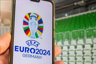 Symbolic image UEFA-EURO 2024: Smartphone with the EURO logo in front of an empty stadium