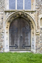 West door Cratfield village parish church, Suffolk, England, UK with spandrel figures of woodwose