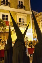 Nazarenos with black robes and typical pointed bonnets, insignia, Semana Santa, procession, night