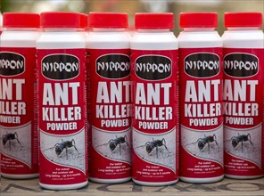 Plastic containers of Nippon brand ant killer powder on shelf display in garden centre, UK