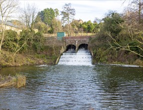 Bridge and weir with rushing water on River Marden, Bremhill, Calne, Wiltshire, England, UK