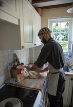Young man kneading dough on kitchen surface