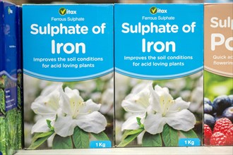Cardboard boxes of Vitax Ferrous Sulphate, Sulphate of iron, on shelf display in garden centre, UK