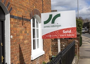 Estate agent property sold sign outside red brick historic house, Marlborough, Wiltshire, England,