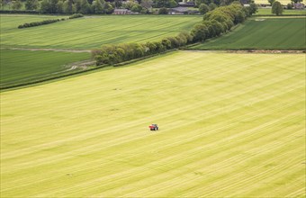 Tractor working in large arable field in Vale of Pewsey, near Woodborough, Wiltshire, England, UK