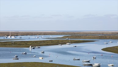 Coastal landscape of salt marsh with boats moored in meandering river drainage channels along the