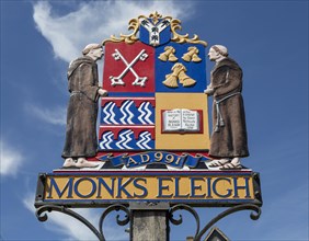 Two monks included in the village sign for Monks Eleigh, Suffolk, England, UK