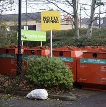 Rubbish bag dumped beneath No Fly Tipping sign, Sainsbury's recycling centre, Calne, England,
