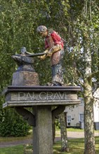 Model of blacksmith working on village sign for Palgrave, Suffolk, England, UK
