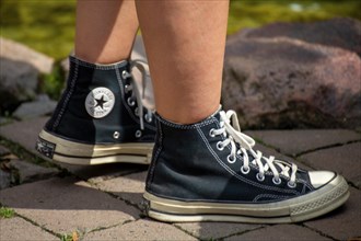 Close-up of black Chucks, worn by a young woman