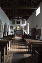 View past wooden pews to chancel arch and altar in sanctuary in the church at Milton Lilbourne,