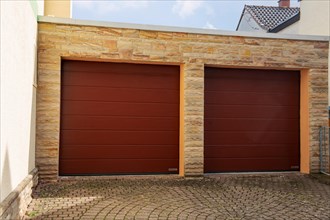 Two red sectional doors from the manufacturer Hoermann on the garage of a detached house