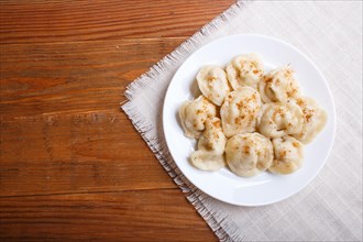 Dumplings on a linen tablecloth on a brown wooden background. top view, flat lay, copy space