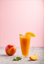 Glass of peach juice on a gray and pink background. Morninig, spring, healthy drink concept. Side