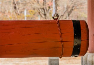 Closeup of large red wooden gong used at Buddhist temple to ring large bronze bell in South Korea