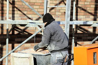 Bricklaying, clinker brick work. Bricklayers clad the facade of a detached house with clinker
