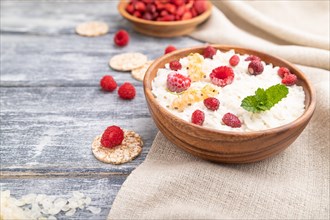 Rice flakes porridge with milk and strawberry in wooden bowl on gray wooden background and linen