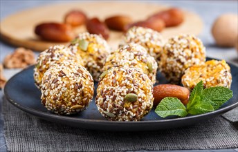 Energy ball cakes with dried apricots, sesame, linen, walnuts and dates with green mint leaves on a