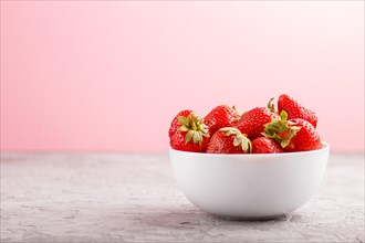 Fresh red strawberry in white bowl on gray and pink background. side view, close up, selective