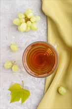 Glass of green grape juice with green textile on a gray concrete background. Morninig, spring,
