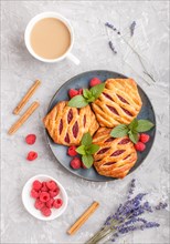 Puff pastry buns with strawberry jam on blue ceramic plate on gray concrete background, cup of