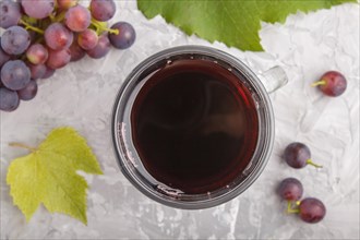 Glass of red grape juice on a gray concrete background. Morninig, spring, healthy drink concept.