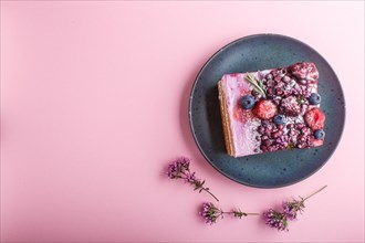 Berry cake with milk cream and blueberry jam on blue ceramic plate on a pink pastel background. top