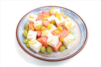 Vegetarian salad with watermelon, feta cheese, and grapes on blue ceramic plate isolated on white