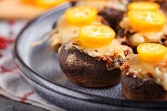 Stuffed fried champignons with cheese, kumquats and green peas on a gray concrete background.