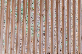 Vertical wooden slats in wall of building with blurred grassy hill in background in South Korea