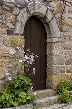 House facade with entrance door, quarry stone house, small flower bed with autumn anemone, Ile de