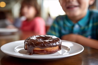 Plate with chocolate donut on kitchen table with young child in background. Concpet for unhealthy