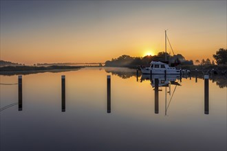 Sunrise in Prerow harbour with boats and a reflection in the water