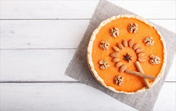 Traditional american sweet pumpkin pie decorated with nuts, on white wooden background. top view,