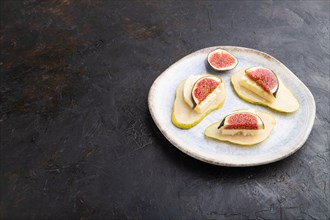 Summer appetizer with pear, cottage cheese, figs and honey on ceramic plate on a black concrete