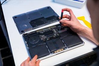 Close-up of an unrecognizable man repairing a digital tablet in a IT workshop
