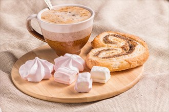 Sweet buns, meringues and coffee cup on a wooden board and linen tablecloth