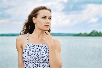 Portrait of cute woman touching her chin at lake